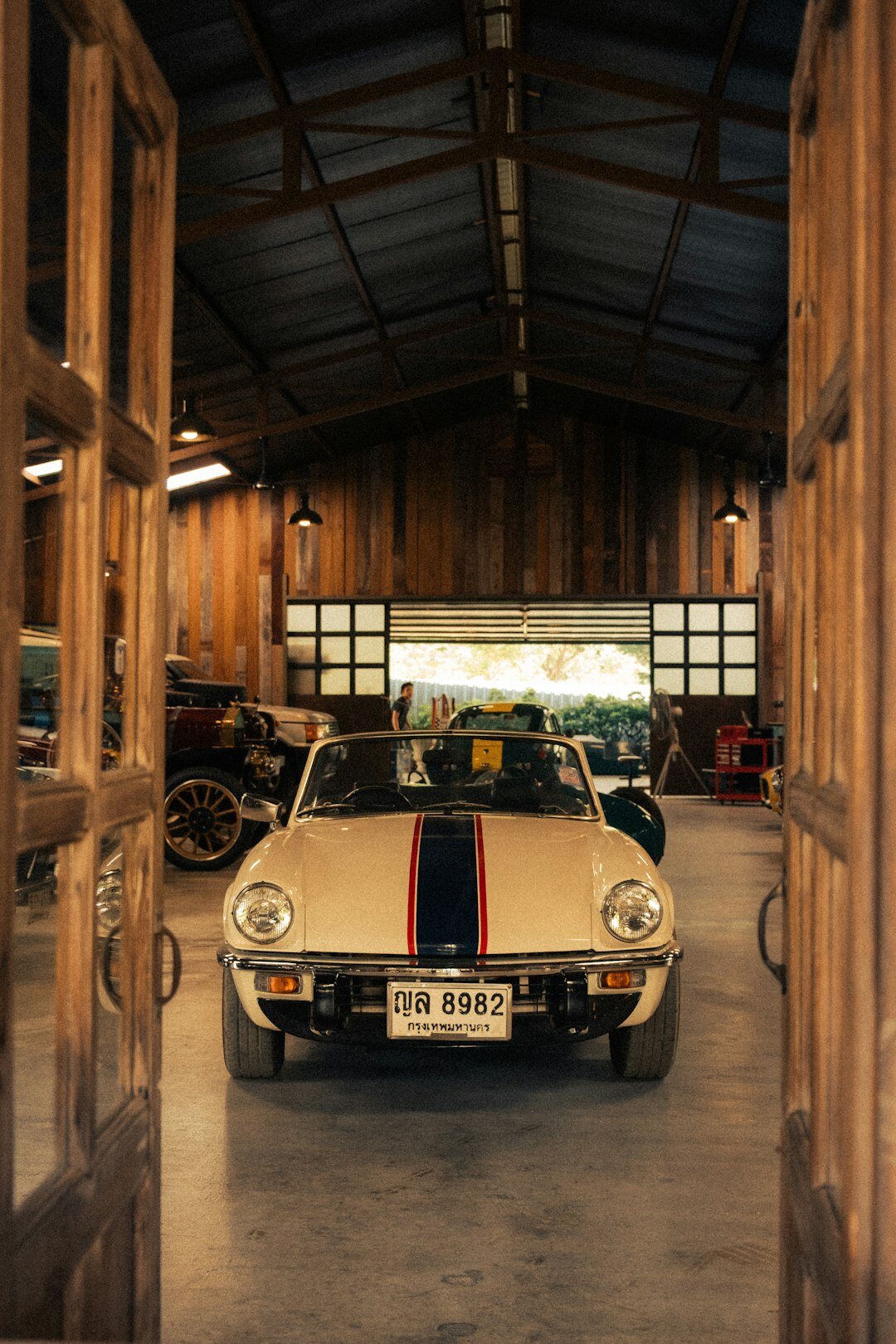 Dimly lit private garage with several covered and uncovered classic cars